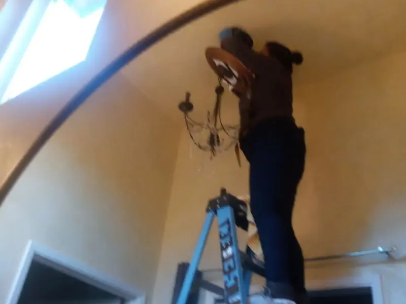 Electrician installing a chandelier in a Greenfield residence